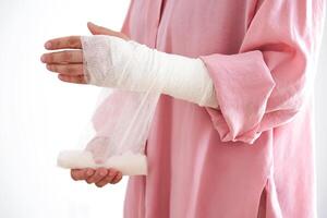 A woman in a pink shirt holds a bandage and puts a bandage on her arm. photo