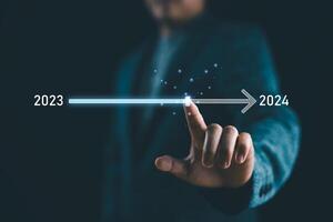 Businessman touch on virtual bar status to change from 2023 to 2024. start new business and new life. New year's start-up. countdown of merry Christmas and happy new year by technology concept. photo