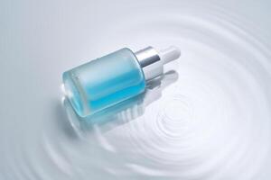 Bottles of cosmetics with a dropper in water on a blue background. photo