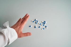 Hand reaches out to a white and blue pill on a blue background. photo