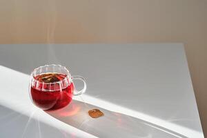 Glass mug with hot black tea on the table. photo