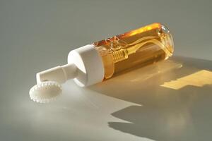 Beige facial foam with a dispenser and brush in the rays of the setting sun. photo