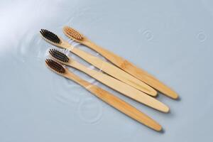 Natural bamboo toothbrushes in water on a blue background. photo