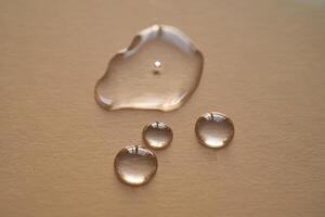 Beautiful volumetric drops of cosmetic product on a beige background. photo