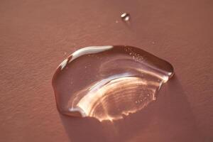 Beautiful volumetric drop of cosmetic product on a pink background. photo