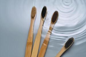 Natural bamboo toothbrushes in water on a blue background. photo