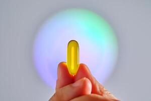 Capsule of omega 3 in hand against the background of a glowing circle. photo