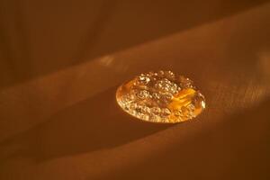 Drop of serum shimmering in the sun on a beige background. photo