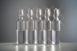 Five ampoules for injection with medicines on a grey background. photo