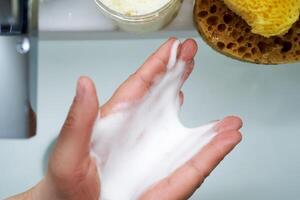 Foam cleanser in female hands over the sink. photo
