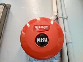 Manual call point tool for fire alarm system, red installed on the wall photo
