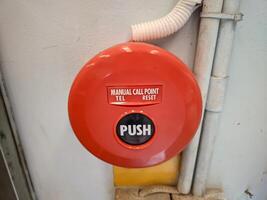 Manual call point tool for fire alarm system, red installed on the wall photo