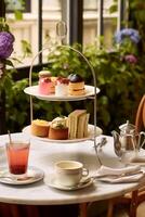 Afternoon tea in the restaurant garden, English tradition and luxury service, tea cups, cakes, scones, sanwiches and desserts, holiday table decor and afternoon tea stand, photo