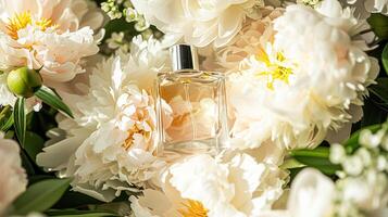 Perfume bottle in flowers, fragrance on blooming background, floral scent and cosmetic product photo