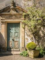 Entrance to a historic manor, framed by antique architectural elements and flanked by potted topiaries, features an aged door photo
