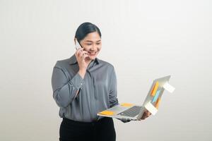 Mujer de negocios asiática hablando por teléfono con la mano sujetando el portátil foto