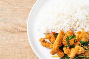 stir-fried fried fish with basil and chili in thai style topped on rice photo