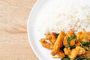stir-fried fried fish with basil and chili in thai style topped on rice photo