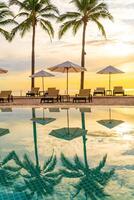 sombrilla y silla alrededor de la piscina en el hotel resort para viajes de placer y vacaciones cerca del mar océano playa foto