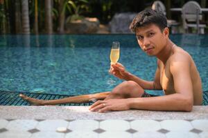 un hombre tiene un descanso en el piscina y disfrutando vaso de sabroso frío blanco vino durante vacaciones. viaje vacaciones. verano vacaciones. foto