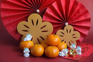 chino nuevo año de el continuar festival concepto. mandarín naranja, rojo sobres, continuar y oro lingote con rojo papel aficionados. chino personaje da Ji da li sentido genial suerte genial ganancia. foto