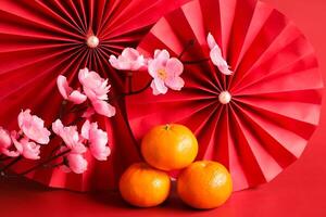 Chinese New Year of the dragon festival concept. Mandarin orange, red envelopes and gold ingot with red paper fans. Traditional holiday lunar New Year. photo