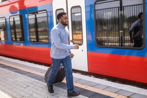 Man running to a leaving train along railway station with suitcase. photo