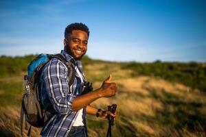 joven hombre disfruta excursionismo en naturaleza y demostración pulgar arriba. foto