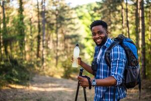 joven hombre disfruta excursionismo y Bebiendo energía beber. foto