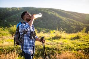 joven hombre disfruta excursionismo y Bebiendo energía beber. foto