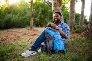 joven caminante utilizando prismáticos mientras descansando en naturaleza. foto