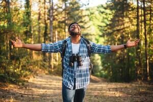 contento joven hombre caminante con brazos elevado disfruta en el naturaleza. foto