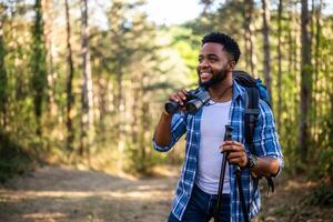 joven hombre disfruta utilizando prismáticos y excursionismo en naturaleza. foto