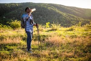 joven hombre disfruta excursionismo y Bebiendo energía bebida foto