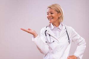 Portrait of mature female doctor gesturing on gray background photo