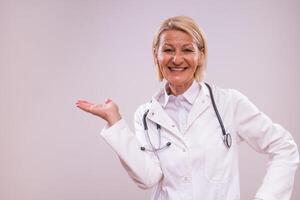 Portrait of mature female doctor gesturing on gray background photo