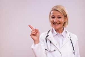 Portrait of mature female doctor pointing on gray background. photo