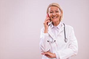 Portrait of mature female doctor using mobile phone on gray background. photo