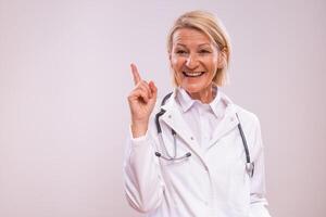 Portrait of mature female doctor having idea on gray background. photo