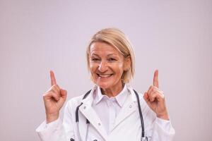 Portrait of mature female doctor pointing on gray background. photo