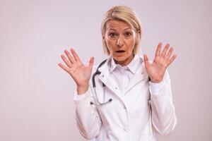 Portrait of mature female doctor in panic on gray background. photo