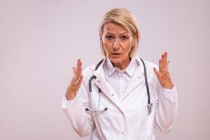 Portrait of angry mature female doctor shouting on gray background photo