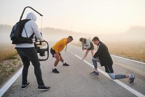 detrás el lente. camarógrafo capturas Atletas calentamiento arriba para Mañana correr. foto