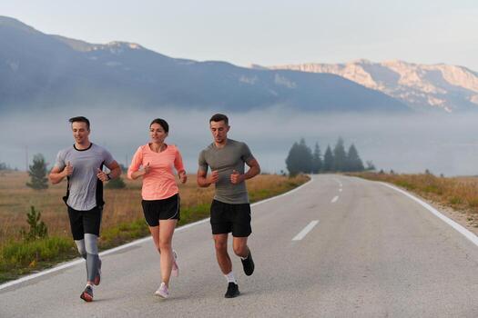 A group of friends, athletes, and joggers embrace the early morning hours as they run through the misty dawn, energized by the rising sun and surrounded by the tranquil beauty of nature photo
