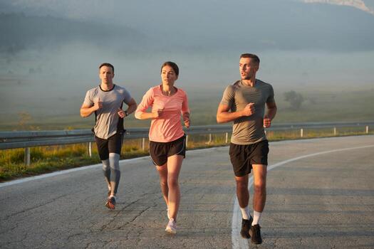 A group of friends, athletes, and joggers embrace the early morning hours as they run through the misty dawn, energized by the rising sun and surrounded by the tranquil beauty of nature photo