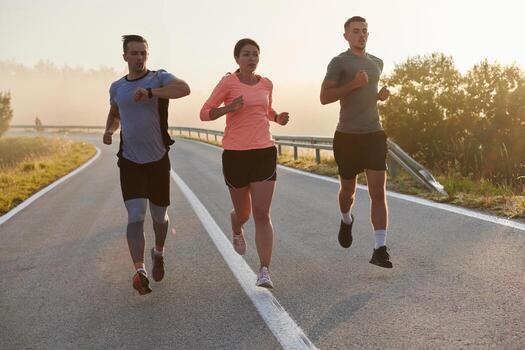 A group of friends, athletes, and joggers embrace the early morning hours as they run through the misty dawn, energized by the rising sun and surrounded by the tranquil beauty of nature photo