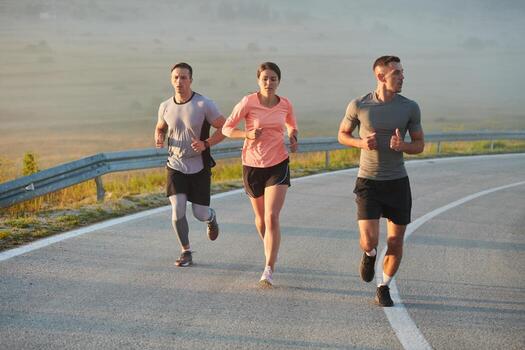A group of friends, athletes, and joggers embrace the early morning hours as they run through the misty dawn, energized by the rising sun and surrounded by the tranquil beauty of nature photo