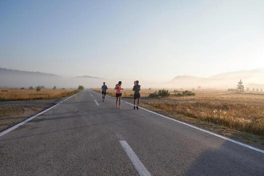 A group of friends, athletes, and joggers embrace the early morning hours as they run through the misty dawn, energized by the rising sun and surrounded by the tranquil beauty of nature photo