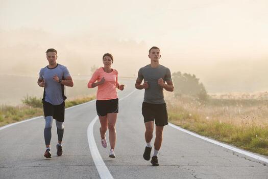 A group of friends, athletes, and joggers embrace the early morning hours as they run through the misty dawn, energized by the rising sun and surrounded by the tranquil beauty of nature photo