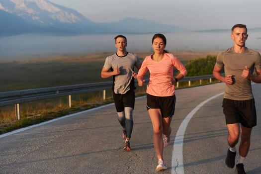 A group of friends, athletes, and joggers embrace the early morning hours as they run through the misty dawn, energized by the rising sun and surrounded by the tranquil beauty of nature photo
